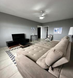 a living room with a large couch and a television at AP Aconchegante a 60 Metros da Praia, vista mar 302 in Praia Grande