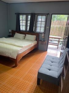 a bedroom with a bed and a chair and windows at KANNIKA RESORT in Ko Chang