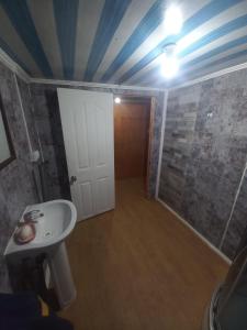 a bathroom with a white sink and a door at Casa de descanso in Punta Arenas