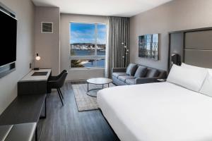 ポーツマスにあるAC Hotel by Marriott Portsmouth Downtown/Waterfrontのベッドとリビングルームが備わるホテルルームです。