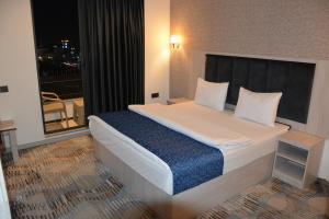 a bedroom with a large white bed with a window at MyFlower 3 Hotel in Erbil