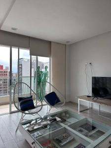 een woonkamer met 2 stoelen en een glazen tafel bij Ole Towers Apartment in Barrio Norte in San Miguel de Tucumán