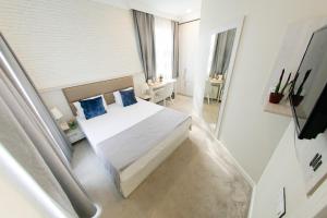 um quarto com uma cama branca e almofadas azuis em Zimmer Boutique Hotel em Baku