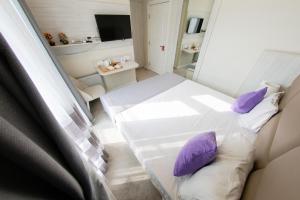 a small room with a white bed and purple pillows at Zimmer Boutique Hotel in Baku