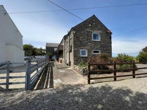 a stone building with a fence next to it at Idyllic rural retreat with one bedroom and parking in East Portlemouth