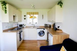 a kitchen with white cabinets and a washing machine at Idyllic rural retreat with one bedroom and parking in East Portlemouth