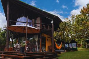 a house with a porch with chairs and an umbrella at Ilha privativa - Rio Paraguaçu in Cachoeira