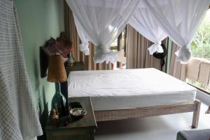 a bedroom with a white bed with curtains and a table at Ilha privativa - Rio Paraguaçu in Cachoeira
