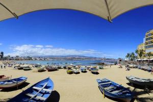 - une plage avec des bateaux sur le sable et un parasol dans l'établissement Kalima Canteras Loft, à Las Palmas de Gran Canaria