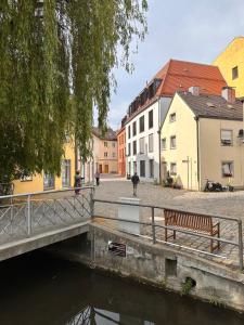 a bridge over a river with a bench and buildings at Stadtflair Freising - moderne Wohnung im Zentrum in Freising
