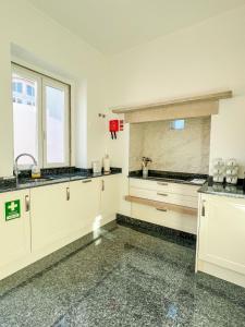 uma cozinha com armários brancos e um lavatório em Chalet do Eléctrico 92' em Sintra