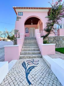 uma casa cor-de-rosa com escadas e um quadro. em Chalet do Eléctrico 92' em Sintra
