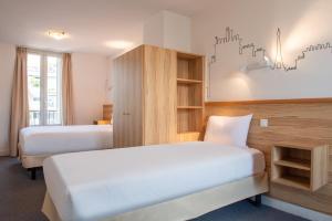 a hotel room with two beds and a cabinet at Au Pacific Hotel in Paris +24 photos