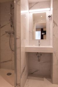 La salle de bains est pourvue d'un lavabo et d'une douche. dans l'établissement Au Pacific Hotel, à Paris