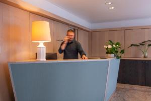 a man is standing behind a desk with a lamp at Au Pacific Hotel in Paris