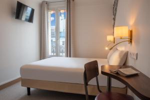 Cette chambre comprend un lit, un bureau et une fenêtre. dans l'établissement Au Pacific Hotel, à Paris