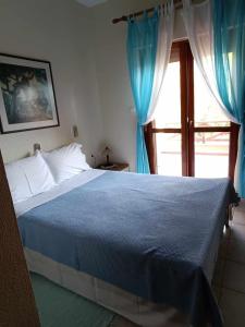 Un dormitorio con una cama y una ventana con cortinas azules. en Georgia's house, en Nikiti