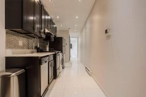 a kitchen with black cabinets and a white tile floor at 5-Bedroom NYC Apartment in New York