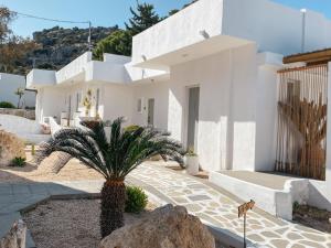 ein weißes Haus mit einer Palme davor in der Unterkunft Ladiko Inn Hotel Faliraki -Anthony Quinn Bay in Faliraki