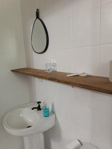 a white bathroom with a sink and a mirror at Apezinho 209 in São Leopoldo