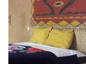 a bed with two yellow pillows and a wall at Bivouac Liguera chez Ahmed in Mhamid