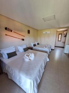 Habitación de hotel con 3 camas con sábanas blancas en Villa Garcez, en Jaguaripe