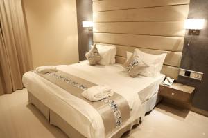 a hotel room with a bed with white sheets and pillows at الماسةالتاج للشقق الفندقية in Hail