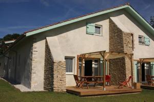 ein Cottage mit einer Terrasse und Stühlen davor in der Unterkunft La Maison des Eyres - Gîte Le Fadet in Pey