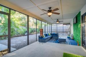 a living room with a ceiling fan and large windows at Sunny Palm Harbor Home with Private Pool and Hot Tub! in Palm Harbor