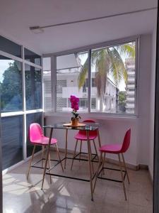 a dining room with pink chairs and a table at R-8 Amplio apartamento en zona turística. in Panama City