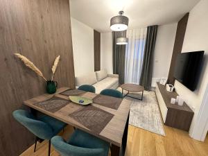 a living room with a wooden table and blue chairs at FORESTA Apartment Jahorina in Jahorina