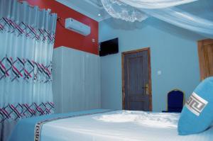 布松布拉的住宿－Kinindo Light Hotel，一间卧室设有一张床和红色及白色的墙壁