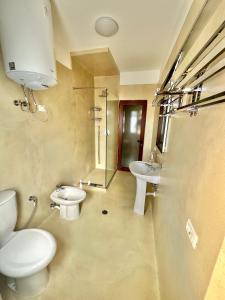y baño con 2 aseos, lavamanos y ducha. en Amos City Center Apartment Tirana, en Tirana