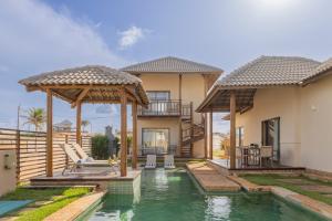 a villa with a swimming pool and a house at The Coral Beach Resort by Atlantica in Trairi