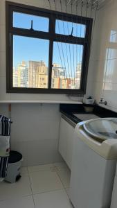 ein Bad mit einem Fenster und einer Waschmaschine in der Unterkunft Apartamento perto da praia em Itapoã in Vila Velha