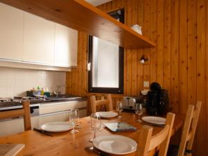 a kitchen with a wooden table with plates and glasses at Val d'Isère - Pied des pistes 4 pers in La Daille