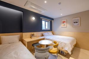 Zimmer mit 2 Betten und einem Tisch in der Unterkunft Hithere City Myeongdong in Seoul