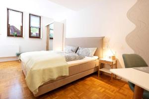 LangenthalにあるFerienapartment Am Gaulsbachのベッドとテーブルと2つの窓がある寝室