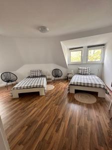 two beds in a room with wooden floors and two windows at Zimmer im Zentrum - in der Nähe zum Hauptbahnhof in Paderborn
