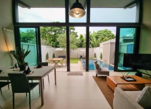 Horizon Vista Pool Villa Family Retreat Bangtao في فوكيت تاون: غرفة معيشة مع طاولة وكراسي ونافذة كبيرة