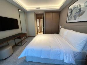 - une chambre avec un grand lit blanc et une télévision à écran plat dans l'établissement Dreamy 2BR Haven, Downtown Bliss, à Dubaï