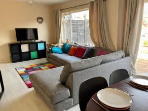a living room with a gray couch with colorful pillows at CROYDON Spacious 3 Bedroom Family House in Addington
