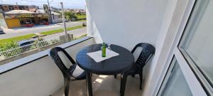 een zwarte tafel en stoelen op een balkon met een raam bij Camelo locação de Suítes Individuais Pousada com Cozinha e Sala Compartilhada in Arroio do Silva