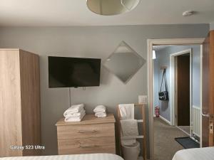 a bedroom with a tv on a wall with a dresser at A Home From Home 3 in Plymouth