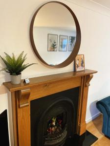 una chimenea con un espejo redondo encima en 3 bed home in Cheltenham Town Centre with FREE PARKING for 1 car en Cheltenham