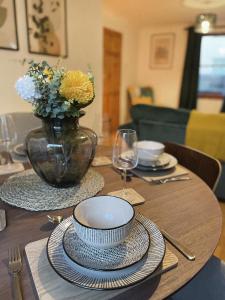 Una mesa de madera con platos y un jarrón con flores. en 3 bed home in Cheltenham Town Centre with FREE PARKING for 1 car, en Cheltenham