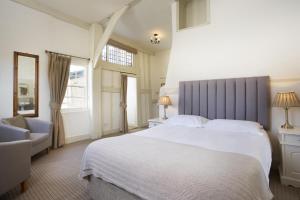 een slaapkamer met een groot wit bed en een stoel bij The George Hotel & Brasserie, Cranbrook in Cranbrook