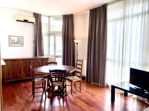 sala de estar con mesa, sillas y TV en Appartamenti Leonardo, en Brescia