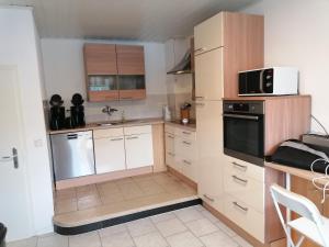 a kitchen with white cabinets and black appliances at Ferienanlage - Am Moselufer in Kövenig