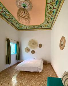 um quarto com uma cama com um tecto pintado em Kasbari House em Taghazout